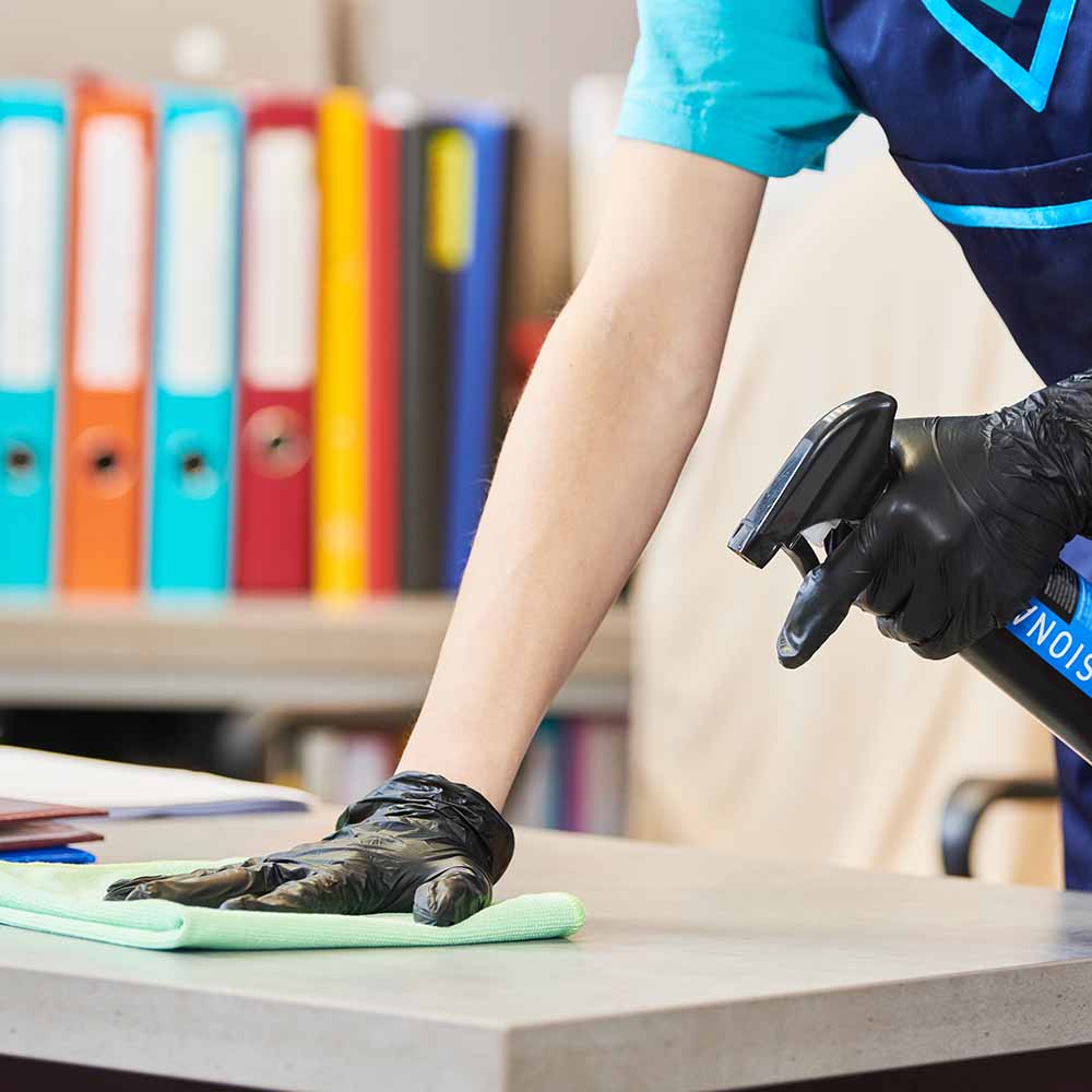 Schreibtisch wird geputzt, Aktenordner im Hintergrund